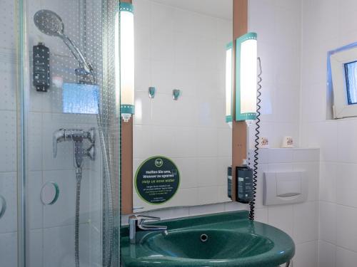 亚琛B&B Hotel Aachen-Hbf的一间带绿色水槽和淋浴的浴室