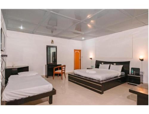 穆索里Shiv Sutra Resorts, Mussoorie的一间卧室配有两张床、一张桌子和一把椅子