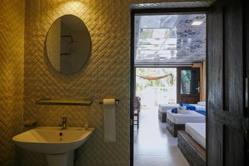 阿鲁甘湾Arugamabay Surf Resort的一间带水槽和镜子的浴室以及两张床