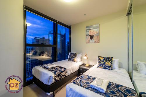 墨尔本Aussie Escape Apartments的一间卧室设有两张床和大窗户