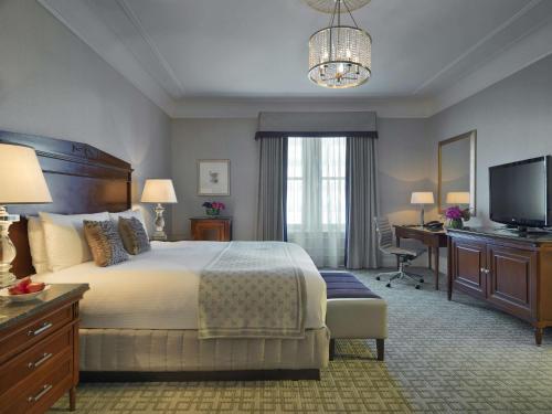波士顿费尔蒙科普利广场酒店的一间卧室配有一张床、一张书桌和一台电视