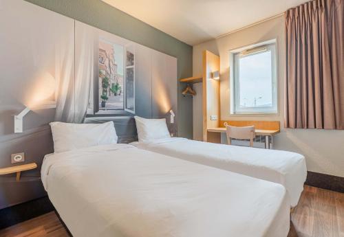 万泽内姆B&B HOTEL Colmar Vignobles Ouest的酒店客房配有两张床和一张书桌