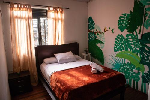 圣罗莎德卡瓦尔Kimaná Hostal的壁画客房内的一间卧室,配有一张床