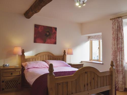 奥斯威斯Granary Cottage的一间卧室配有一张带粉红色枕头的木床。