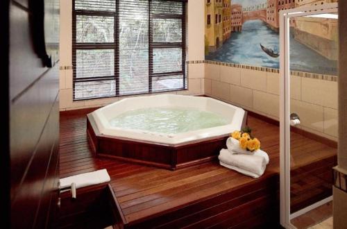 哈特比斯普特Unit H011 Magalies Park Hartbeespoort的带浴缸的浴室和大窗户