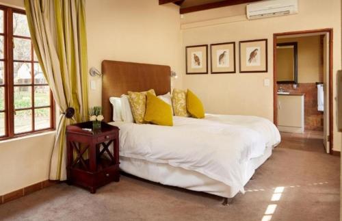 哈特比斯普特Unit H011 Magalies Park Hartbeespoort的卧室配有一张带黄色枕头的大型白色床。
