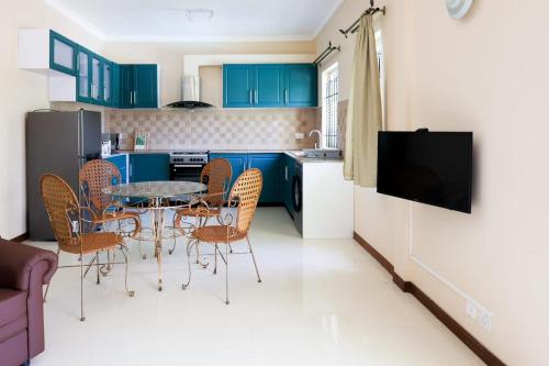 格兰贝伊ibis Apartments - Ground Floor - Summersun Residence - Grand Baie, Pereybere的厨房配有蓝色橱柜和桌椅