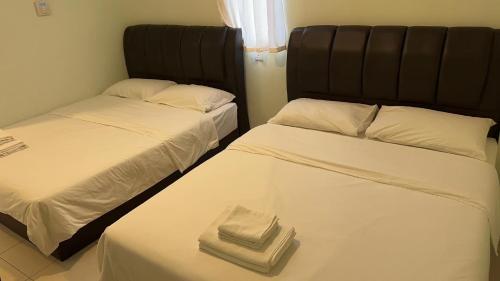 马六甲The Glorious Straits Hotel的两张睡床彼此相邻,位于一个房间里