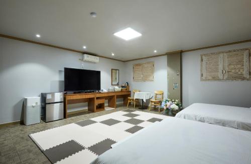 扶安Buan Tree California Hotel的一间卧室配有两张床和一张书桌及电视
