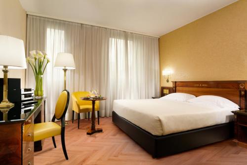 米兰UNAHOTELS Scandinavia Milano的酒店客房配有一张床铺、一张桌子和一张书桌。