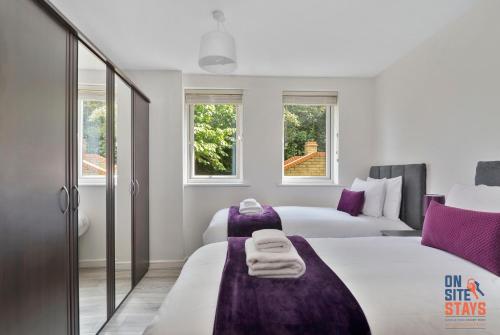 达特福德OnSiteStays - Contemporary 2 Bed Apt with Ensuite, 2 x Free Parking Spaces & a Balcony的一间卧室设有两张床和两个窗户。