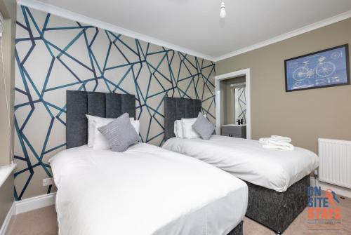 达特福德OnSiteStays - Stylish 4 BR House with Beautiful Outdoor Space, Wi-Fi & Smart TVs的壁画客房内的两张床