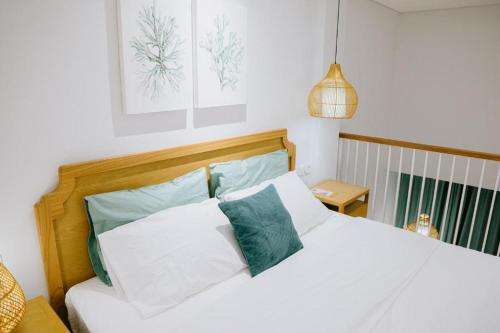 坎古Casa Amarta - Canggu的卧室配有白色床和绿色和白色枕头