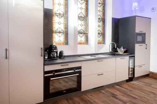 勒米尔蒙LA BELL'CHAPELLE的厨房配有白色橱柜和炉灶烤箱。