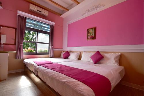 小琉球岛薇多莉亚乡村花园民宿的卧室配有一张带粉红色墙壁的大床