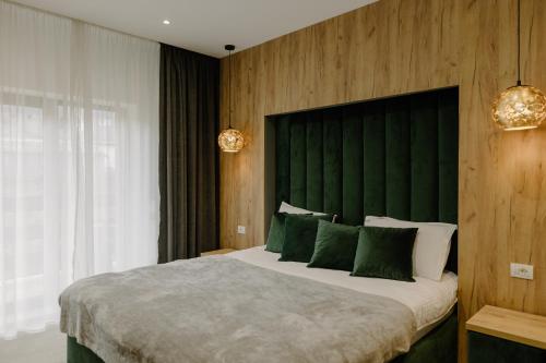 BorlovaHotel Muntele Mic的一间卧室配有一张大床和绿色床头板