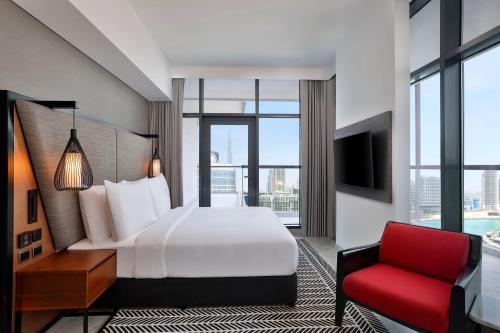 迪拜The First Collection Waterfront的酒店客房,配有一张床和一张红色椅子