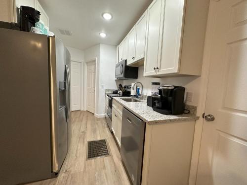 塔拉哈西One unit of a fully renovated duplex near FSU的厨房配有白色橱柜和不锈钢冰箱