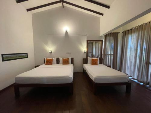 波隆纳鲁沃Hotel Lake Park的配有白色墙壁和木地板的客房内的两张床