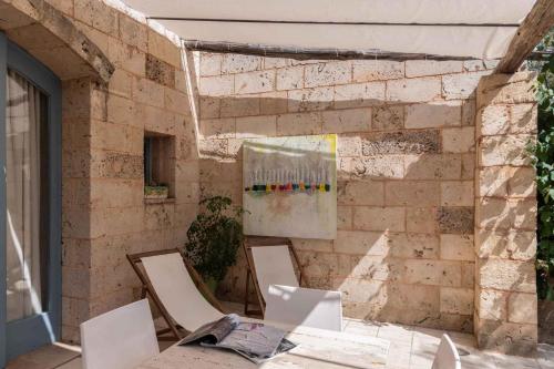 斯蓬加诺Apartments in Spongano/Apulien 20947的一间设有椅子的房间和砖墙上的一幅画