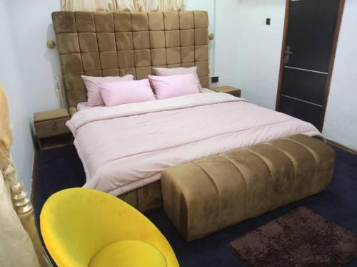 拉各斯Cozy Comforts的一间卧室配有一张大床和一张黄色椅子