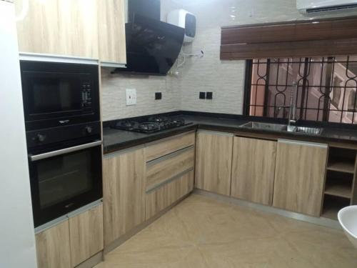 拉各斯Cozy Comforts的厨房配有木制橱柜和炉灶烤箱。