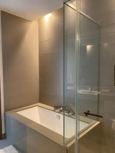 迪拜Modern 2BR and maid room with big terrace city walk的带浴缸的浴室内的玻璃淋浴间