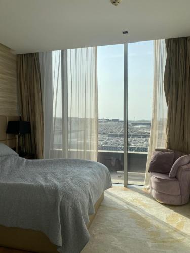 迪拜Modern 2BR and maid room with big terrace city walk的一间卧室配有一张床、一把椅子和一个大窗户