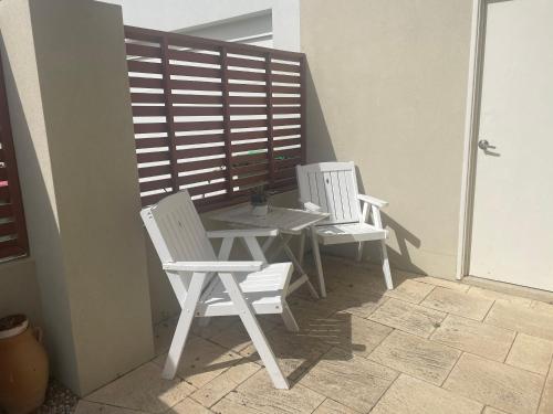 珀斯Ocean Reef Retreat的庭院里设有两把白色的椅子和一张桌子