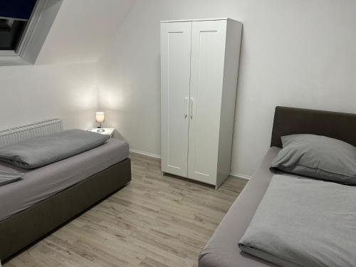 勒讷Wohnen wie zu Hause的一间卧室配有两张床和白色橱柜