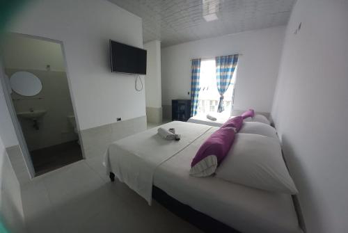 Hotel Oiti的一间卧室配有一张带紫色枕头和镜子的床