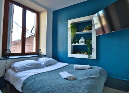 蒙贝利亚尔Studio de 30m² hypercentre très calme的一间卧室设有蓝色的墙壁和一张带毛巾的床。
