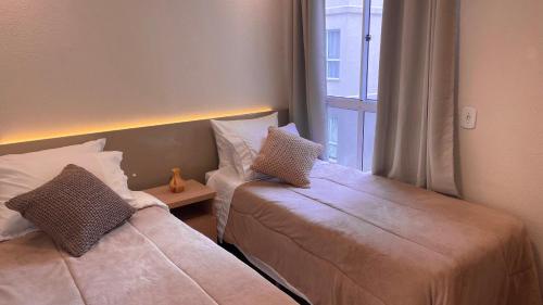 巴热Elegante Apartamento, com ótima localização, na principal avenida de entrada em Bagé的带窗户的客房内的两张床