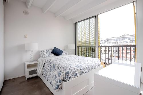 温哥华Modern, Bright & Beautiful, 1 Bedroom Downtown Apt with Rooftop Patio的白色的卧室设有床和大窗户