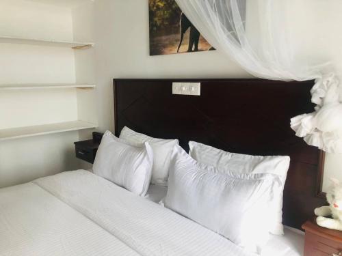 阿洪加拉Ocean Pearl Cottage的一间卧室配有带白色床单和枕头的床。