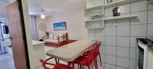马塞约Maceio ferias apto completo a 100 metros da praia的厨房以及带桌子和红色椅子的用餐室。