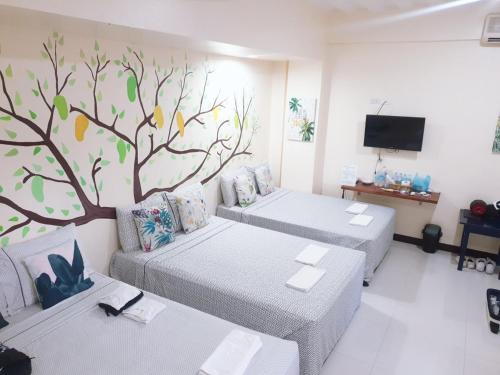 MaribagoHarang Hotel Mactan Lapulapu City Cebu Philippines的一间设有两张床的客房,墙上挂着一幅树壁画
