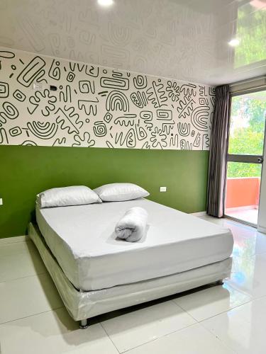 BaranoaHotel Paranawa的一间卧室配有一张白色大床,墙上涂鸦