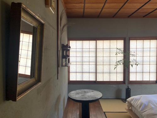 金泽Machiya Guest House Carta的客房设有2扇窗户和桌子。