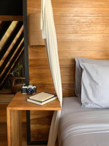 BalianDesa Cabins的一张桌子,上面有摄像头,床上有一本书