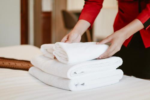邦帕利暹罗素万那普塔布明酒店的把白色毛巾堆在床上的妇女