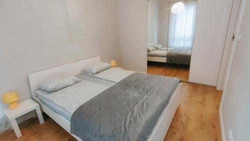华沙FIRST -- Green Żoliborz Apartment 4的一间白色的小卧室,配有床和镜子