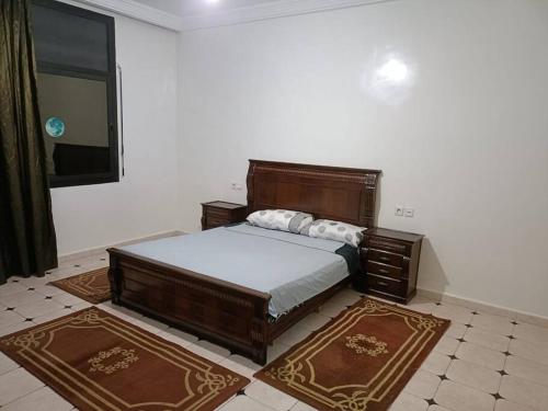 拉巴特Villa à la décoration marocaine的一间卧室配有一张大型木床和2个地毯。