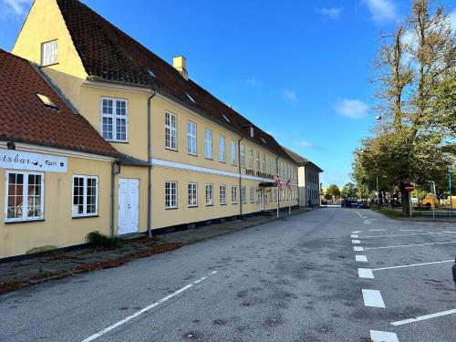 弗雷德里克斯伐克Frederiksværk Hotel的黄色建筑前的一条空街道