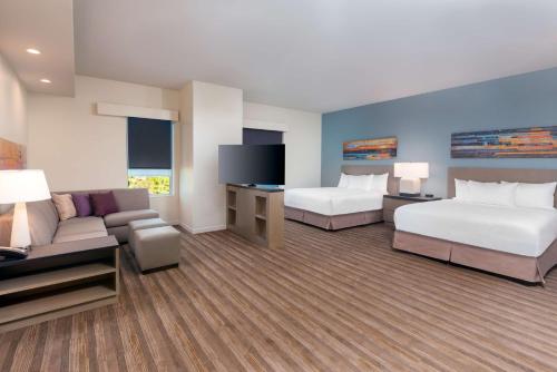 奥兰多Hyatt House Orlando Airport的酒店客房,设有两张床和一张沙发
