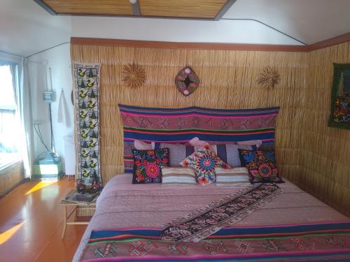 普诺Uros Titicaca Ayni lodge的一间卧室配有一张大床和红色床头板