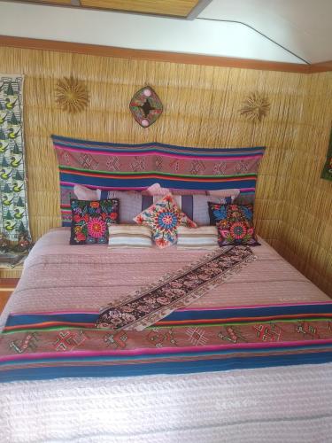 普诺Uros Titicaca Ayni lodge的一间卧室配有一张带粉红色床头板的床