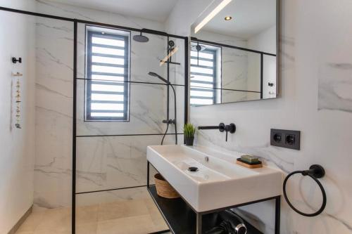 简蒂埃尔Zon&zo Luxurious Apartment in Jan Thiel的白色的浴室设有水槽和淋浴。