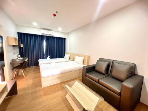 武里南JIA HAUS Hotel Apartment的酒店客房,配有床和沙发