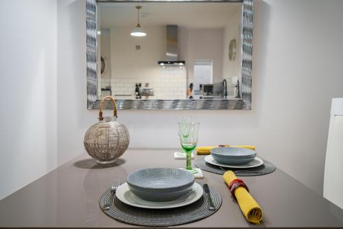 唐克斯特Coppergate Mews Apartment Doncaster 3的一张桌子,上面有盘子和玻璃杯,还有镜子